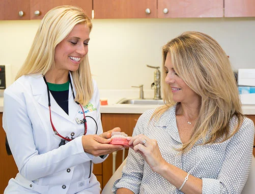 Dental hygienist showing a patient a model of teeth in a treatment room